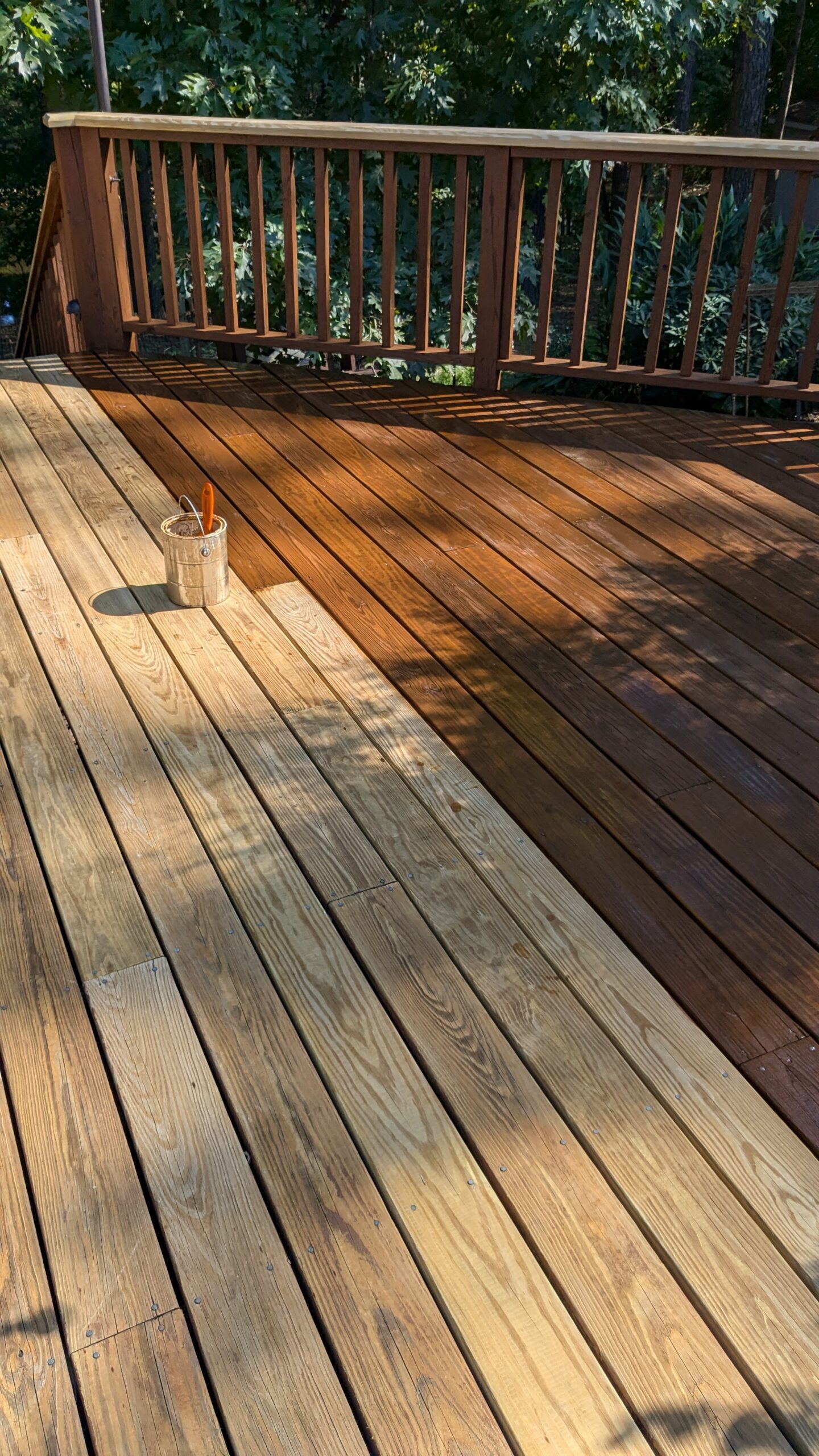Deck boards showing the contrast between stained and unstained wood, with a brush and stain can