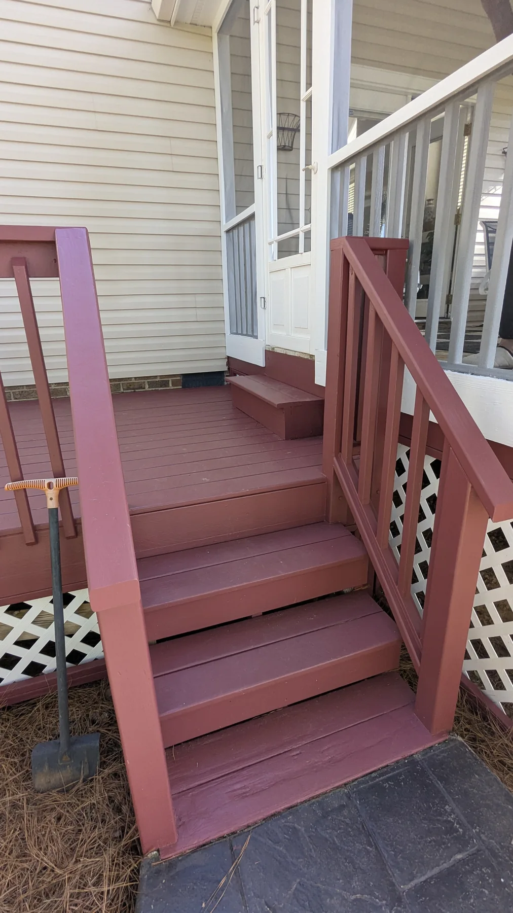 Red painted deck stairs beside white siding