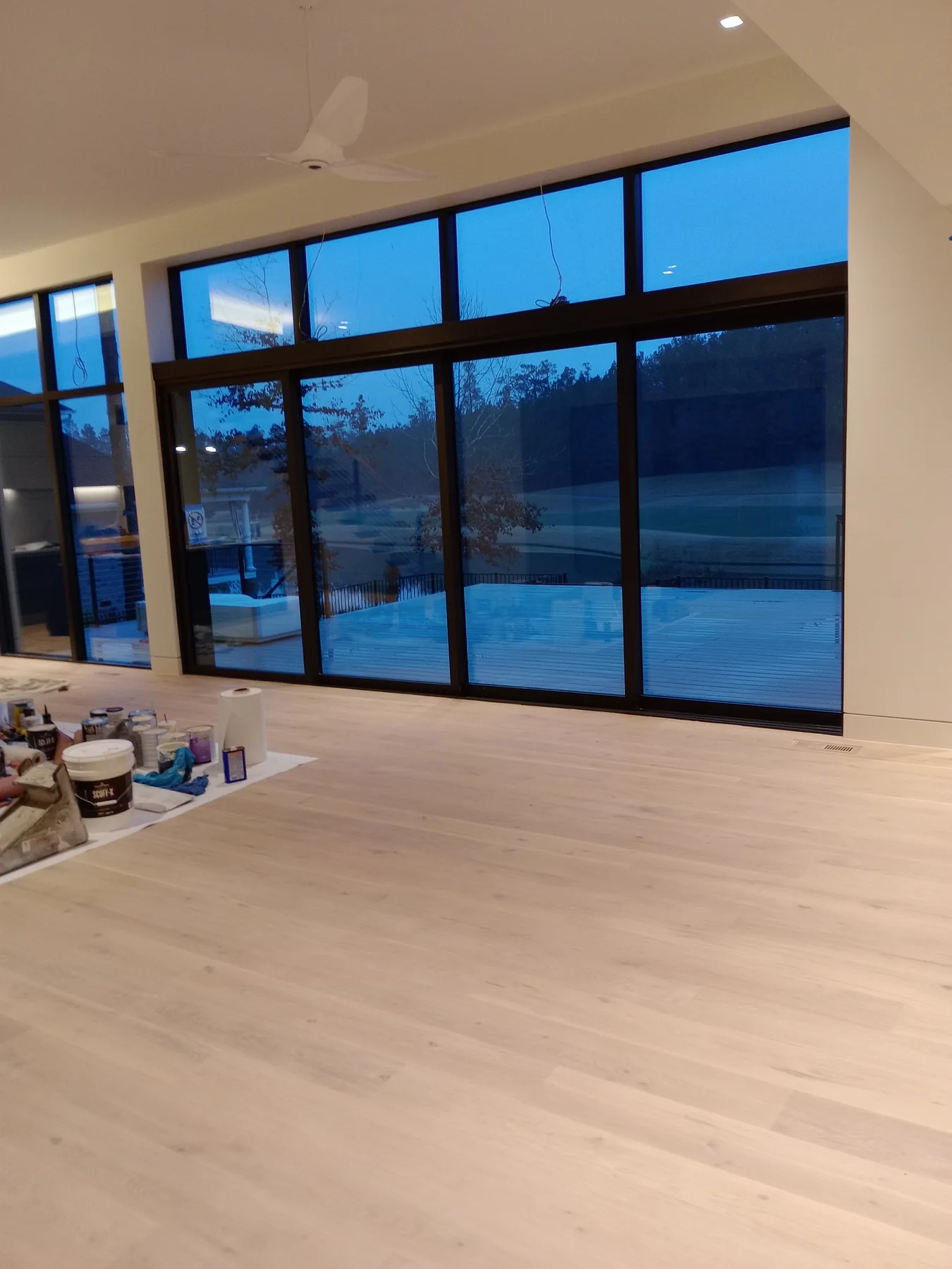 Open-plan interior with tall windows and painting supplies during work