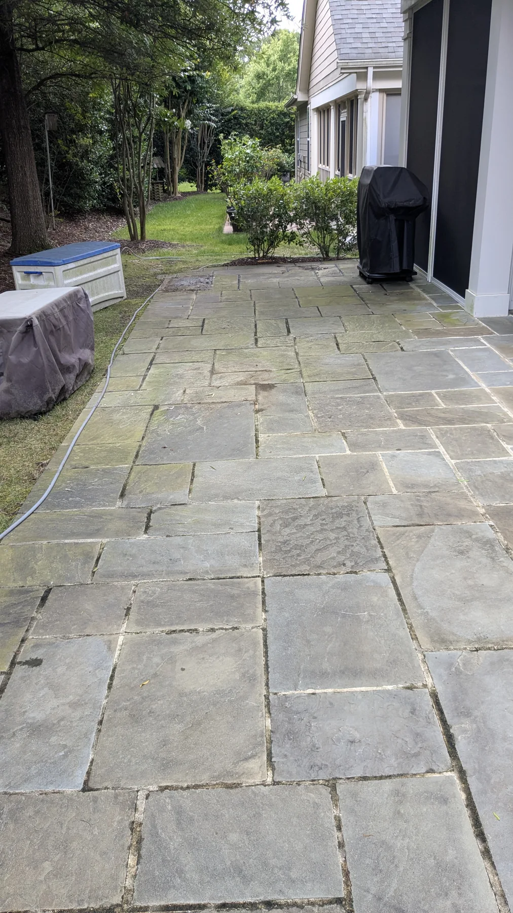 Stone patio showing surface buildup before washing