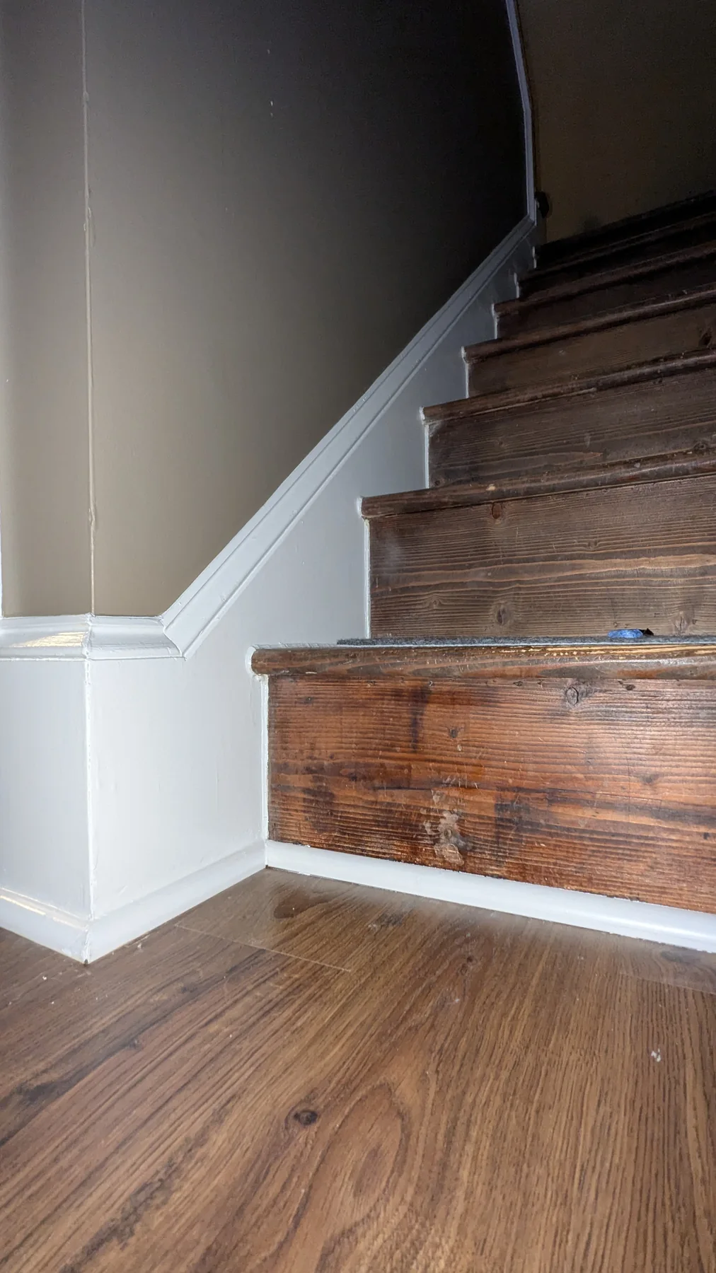 Painted stairwell wall and white stair trim beside wood steps