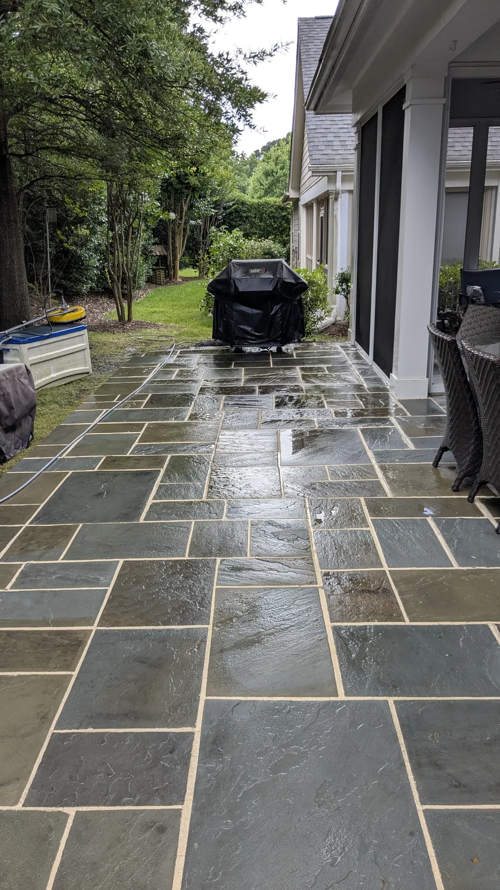 Freshly washed wet stone patio beside a screened porch